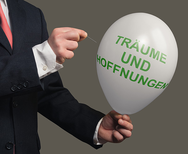 ... denn irgendwann ist auch ein Traum zu lange her Ein Mann im Anzug lässt mit einer Nadel einen Ballon mit der Aufschrift Träume und Hoffnungen platzen